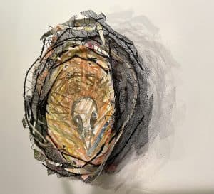 Nest shaped mixed-media construction of cut watercolor painted paper image of bird skull.