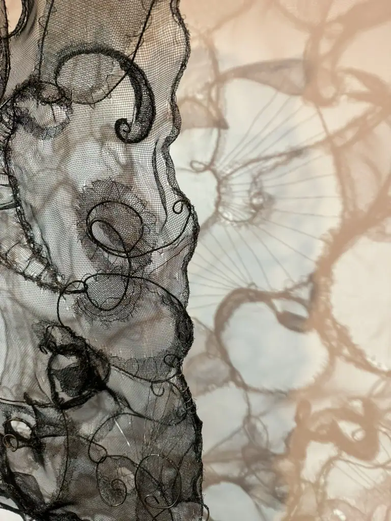 Abstract wire and screen sculpture with intricate loops and curves.