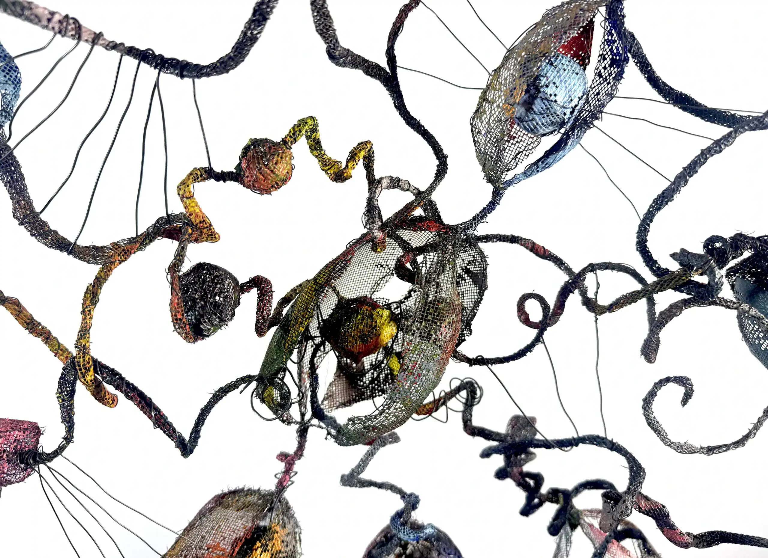 Close-up of intricate wire sculpture with colorful painted screen elements.